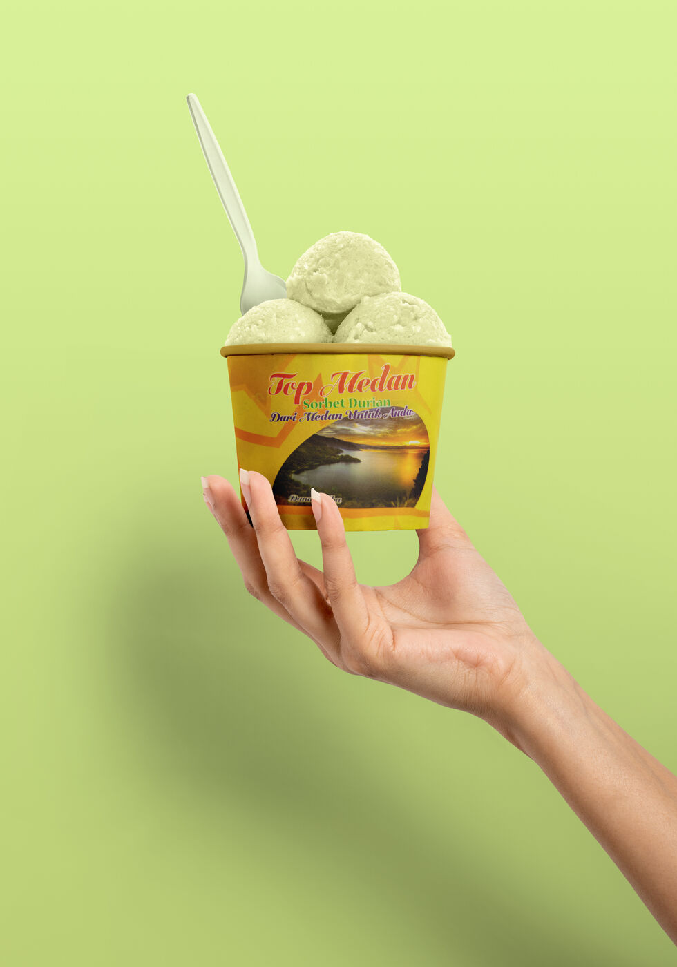 Hand holding a cup of durian sorbet with a spoon